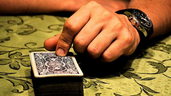 Mans Hand On Top of A Deck of Cards